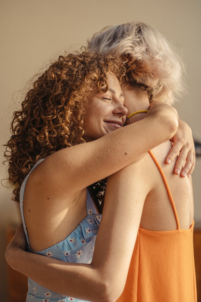 Mastering the First Impression: Your intriguing post title goes here Two women joyfully embracing in a warm, sunny atmosphere, representing love and friendship.